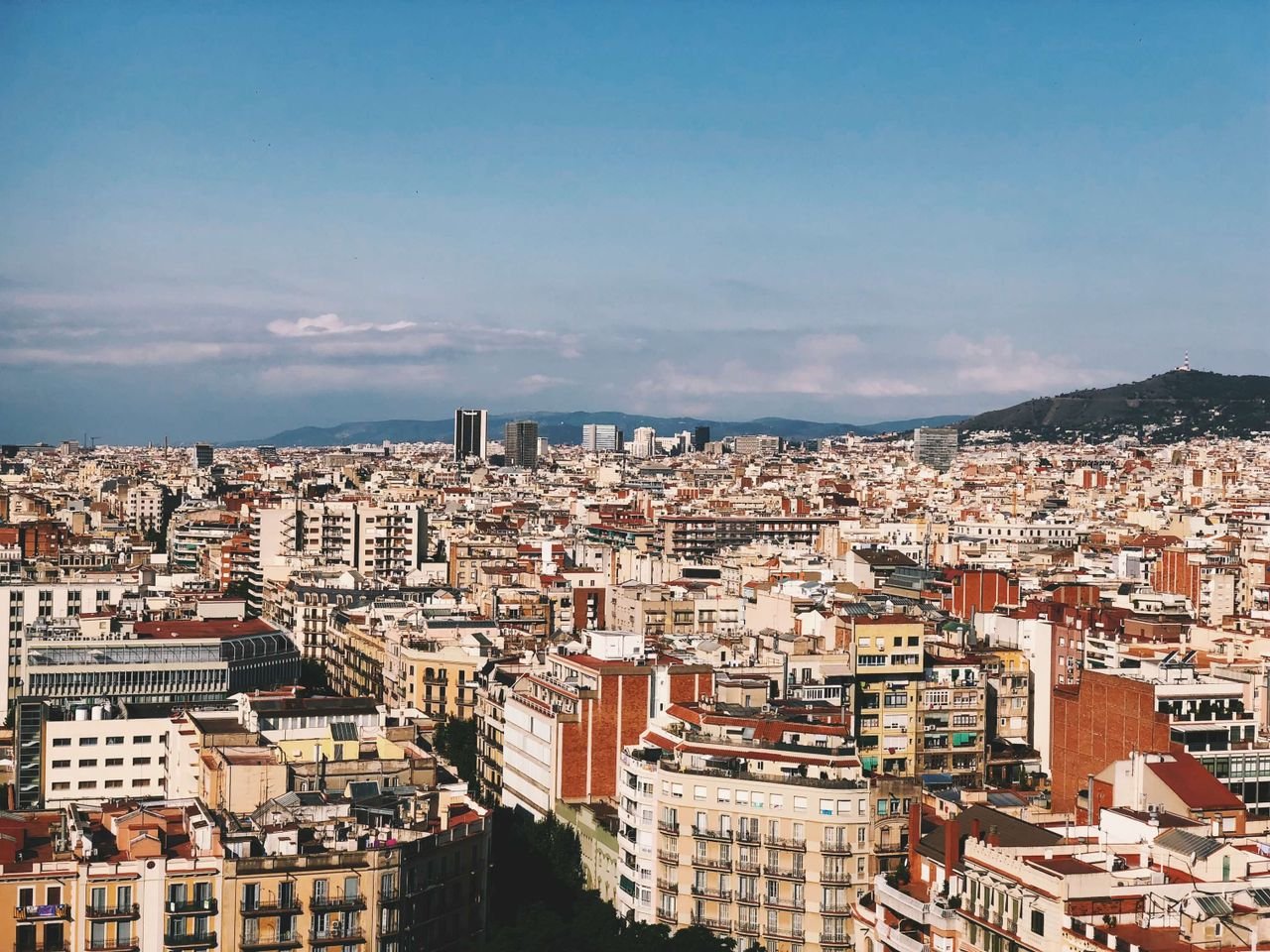 A panoramic view of Barcelona's colorful urban landscape with clear skies, showcasing diverse architecture.